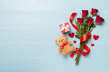Red rose flowers with gift box and soft toy on wooden background, top, view. Valentine's day concept