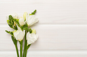 White fresia flower on wooden background, top view