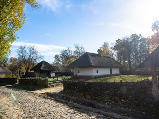 Traditional wooden house with thatched roof and white walls. A small house in a mountain village, Ukraine. Picturesque village in autumn.