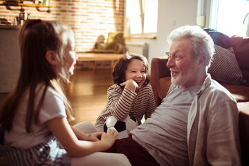 Happy grandfather bonding with grandchildren at home