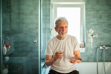 Senior man taking his medication in the bathroom at home