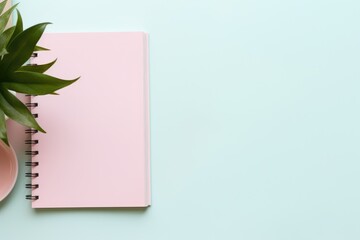 capturing a top view of a blank pink notebook mockup with a spiral binding, nestled next to a...