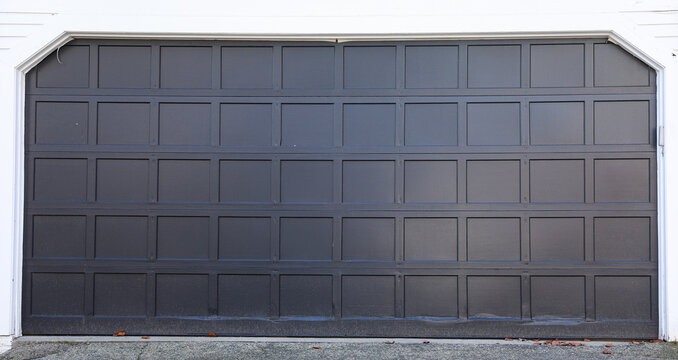 Garage door slightly open, revealing tools and storage boxes inside, sunlight peeking through, suburban house background