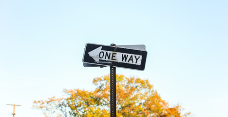 One-way arrow, urban symbol of directional flow and traffic control, against cityscape backdrop