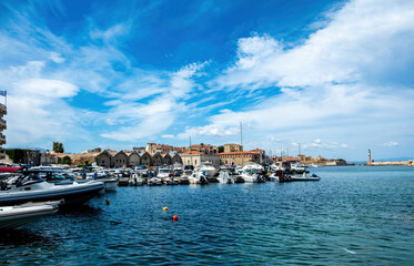 Fototapeta na wymiar Venetian harbour in Old Town of Chania Crete Greece. Moored boat at marina, beacon, sea, blue sky.