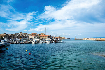 Naklejka premium Venetian harbour in Old Town of Chania Crete Greece. Moored boat at marina, beacon, sea, blue sky.