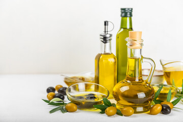 Olive oil in a bottle on a white texture background. Oil bottle with branches and fruits of olives. Place for text. copy space. cooking oil and salad dressing.