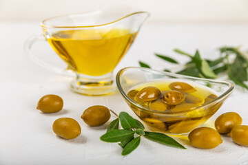 Olive oil in a bottle on a white texture background. Oil bottle with branches and fruits of olives. Place for text. copy space. cooking oil and salad dressing.