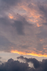 Beautiful sunset sky. Clouds at sunset. A small plane flies in the dark sky