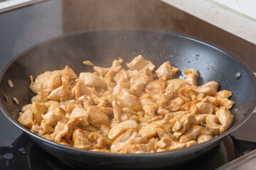 Shredded chicken for frying in a pan. The side dish is tomato juice.