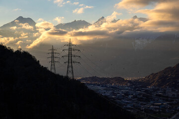 pylons of a high voltage line above the Rhône plain in Switzerland in winter - 693662510