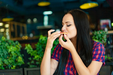 A Woman Enjoying a Delicious Meal. A woman sitting at a table eating a piece of food