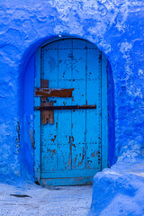 Old door of a house on a street painted blue in the medina of Chefchaouen, Morocco