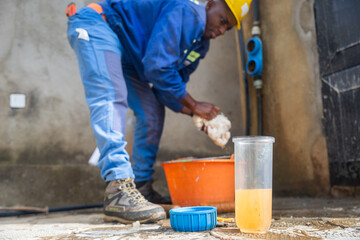 Young African blue collar worker washing the filters' containers. Water filtration concept