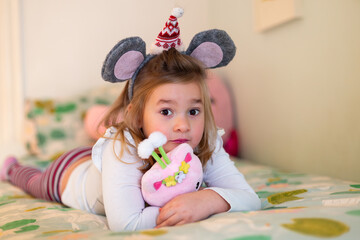 Selective focus view of cute little girl with Christmas mouse ears headband holding tight to a...