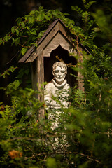 stone religious figure in a wooden structure surrounded by plant life