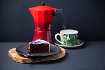 cup of coffee with red coffee pot and cake on a black background 