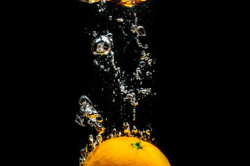 Orange falls into water with splashes
