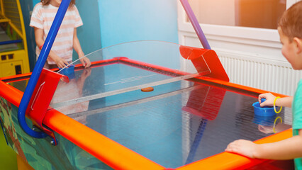 Naklejka premium Boy and girl friends play air hockey together in a children's entertainment center