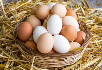 Many eggs lie on the background of hay, top view.