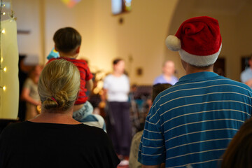 Couple from behind watching the carols church service at Christmas time.