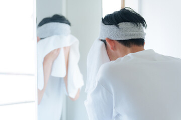 洗顔した顔をタオルで顔を拭く若い男性 - obrazy, fototapety, plakaty