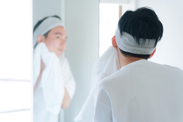 Fototapeta na wymiar 洗顔した顔をタオルで顔を拭く若い男性