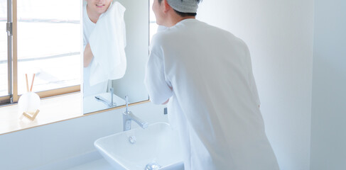 洗顔した顔をタオルで顔を拭く若い男性