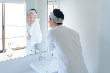 洗顔した顔をタオルで顔を拭く若い男性 - obrazy, fototapety, plakaty