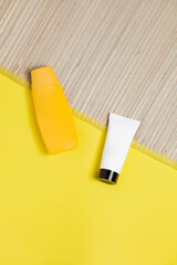 Straw mat on yellow background with bottles of sunscreen. Skin care concept. Summer concept. Copy space.