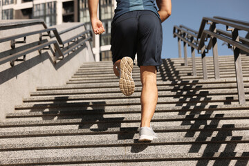 Man running up stairs outdoors on sunny day, closeup