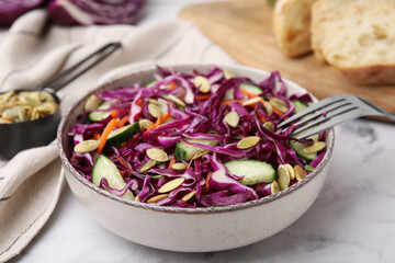 Eating tasty salad with red cabbage and pumpkin seeds on marble table, closeup