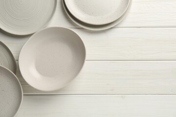 Fototapeta na wymiar Beautiful ceramic plates on white wooden table, flat lay