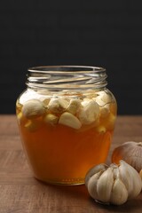 Honey with garlic in glass jar on wooden table