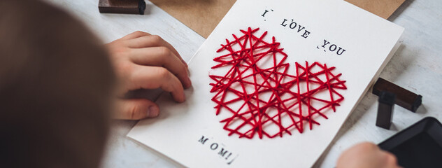 Little kid preparing diy handmade cute post card for Mother's Day with a message I love you mom....