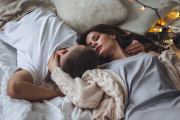 Beautiful happy loving young smiling couple relaxing in bed, looking at each other. Cozy home...