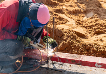 Construction worker welding metal rebar.