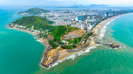 Tuinposter Vung Tau city aerial view with beautiful sunset and so many boats. Panoramic coastal Vung Tau view from above, with waves, coastline, streets, coconut trees and Tao Phung mountain in Vietnam. © huythoai