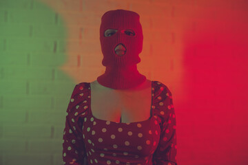 Portrait of a woman wearing a balaclava in red neon light.