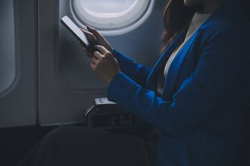 Young Asian business woman talking on smartphone, businesswoman working while flying at plane,...