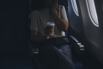 Asian woman enjoying enjoys a coffee comfortable flight while sitting in the airplane cabin,...