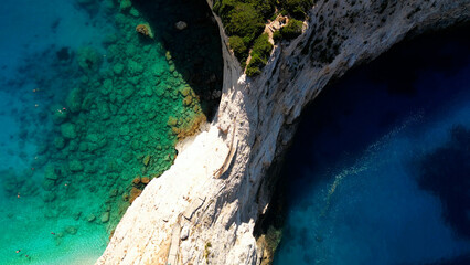 Aerial view of vertical cliff dividing turquoise blue transparent sea water