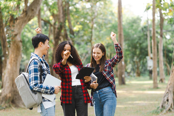 Group of young interracial diverse university students chatting together outside, engaging in a...