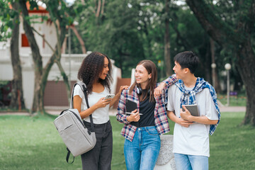 Group of young interracial diverse university students chatting together outside, engaging in a discussion together, college campus, enjoying campus recreation. Happy friends