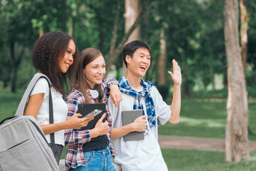 Group of young interracial diverse university students chatting together outside, engaging in a discussion together, college campus, enjoying campus recreation. Happy friends