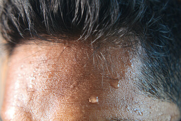 closeup of sweat on forehead against dark background ,