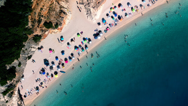 Aerial view of tropical beach with azure transparent sea water, sand, colorful umbrellas