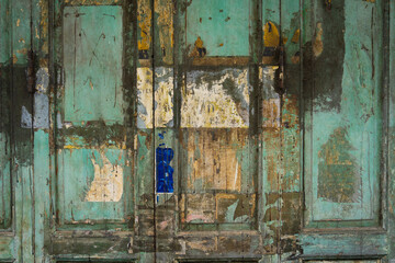 The background of the old door wall is made of wood, painted green, with clumps. Abstract wall texture backdrop.