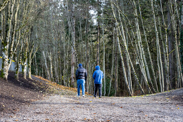 Two men, friends, wearing blue out for a walk on a sunny winter day in a city park
