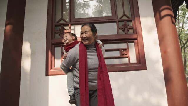 lovely moment of grandmother and baby girl senior asian woman carrying her granddaughter on shoulder playing in the garden joyful lifestyle